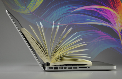Otwarty laptop, na nim otwarta książka. Nad nią widoczne kolorowe fale.