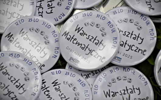 Zdjęcie przypinek promujących wydarzenie. Na każdej znajdują się informacje: Warsztaty matematyczne. Grotniki 2025. PTM. 12 LO, 25 LO, 31 LO, PLO UŁ, PLO PŁ.