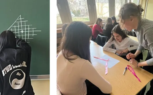 Uczennice pracują w grupach nad zadaniem z geometrii. Na stolikach układają kolorowe paski papieru, a jedna osoba rysuje na tablicy schemat z linii. Nauczycielka pomaga uczennicom podczas pracy.